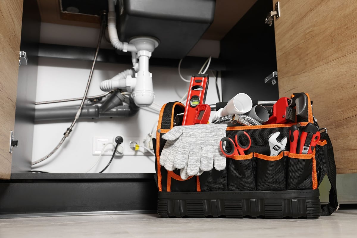Plumber's tool bag under a kitchen sink
