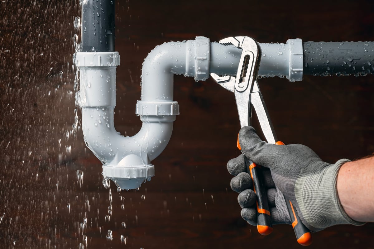 Close-up of a plumber fixing a leak in a sink drain pipe