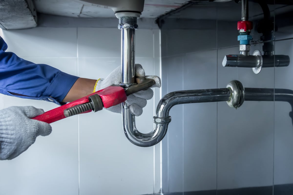 Plumber repairing a clogged bathroom pipe with a wrench